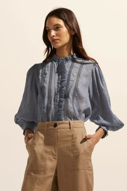 The Swoon top delivers a romantic and artisanal option that has feminine details at its core. A full-length sleeve is gathered at the wrist and finished with a ruffle. Another ruffled edge creates a flattering neckline and front detail. Horizontal ladder lace brings an element of classic elegance to this piece.&nbsp;