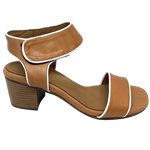 A mid heeled block sandal in tan and piped in white leather. The wide Y back straps around the base of the ankle and is fastened with velcro for convenience.
