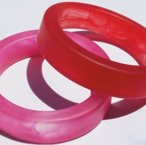 This flat resin bangle will fit a larger hand than others in this range. It is 2cm in width and has squared off edges. Available in white, amber, red and fuchsia pink.
