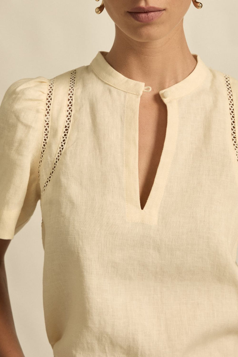 quietly elevated blouse, the Recollect top combines tailoring with soft details.&nbsp;

Lace accents and tulip sleeves lend charm to a clean-lined silhouette.

100% linen composition
circular lace detailing at the shoulder
v-neck split with covered dome button
short gathered tulip sleeve
neat, refined structure