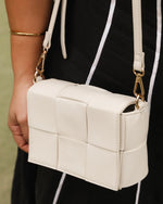 The Josephine Vanilla Crossbody Bag is a statement in both texture and versatility, designed to deliver effortless elegance from day to night. Crafted from woven vegan leather panels, she offers a modern twist on classic texture, adding a refined edge to everyday styling. This women’s woven handbag features a structured silhouette with a magnetic closure to keep your essentials secure, while light gold hardware lends a polished finish. With two interchangeable straps: a sleek vegan leather crossbody and a g