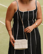 The Josephine Vanilla Crossbody Bag is a statement in both texture and versatility, designed to deliver effortless elegance from day to night. Crafted from woven vegan leather panels, she offers a modern twist on classic texture, adding a refined edge to everyday styling. This women’s woven handbag features a structured silhouette with a magnetic closure to keep your essentials secure, while light gold hardware lends a polished finish. With two interchangeable straps: a sleek vegan leather crossbody and a g