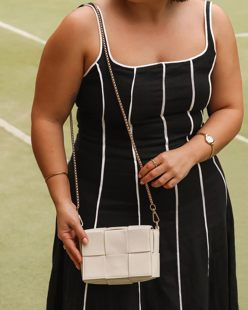 The Josephine Vanilla Crossbody Bag is a statement in both texture and versatility, designed to deliver effortless elegance from day to night. Crafted from woven vegan leather panels, she offers a modern twist on classic texture, adding a refined edge to everyday styling. This women’s woven handbag features a structured silhouette with a magnetic closure to keep your essentials secure, while light gold hardware lends a polished finish. With two interchangeable straps: a sleek vegan leather crossbody and a g
