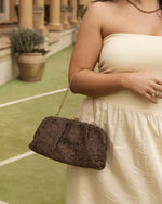 he Goldie Raffia Vanilla Clutch is your statement plus-one for any occasion, designed to elevate your look from daytime celebrations to evening soirées. This evening clutch features a slouchy yet structured silhouette, crafted in a raffia-like texture for a modern take on timeless texture. As a true gold chain clutch, Goldie Raffia Vanilla is finished with both a short and long gold chain strap, giving you the freedom to wear her in hand, over the shoulder, or crossbody. A polished kiss clip closure keeps y