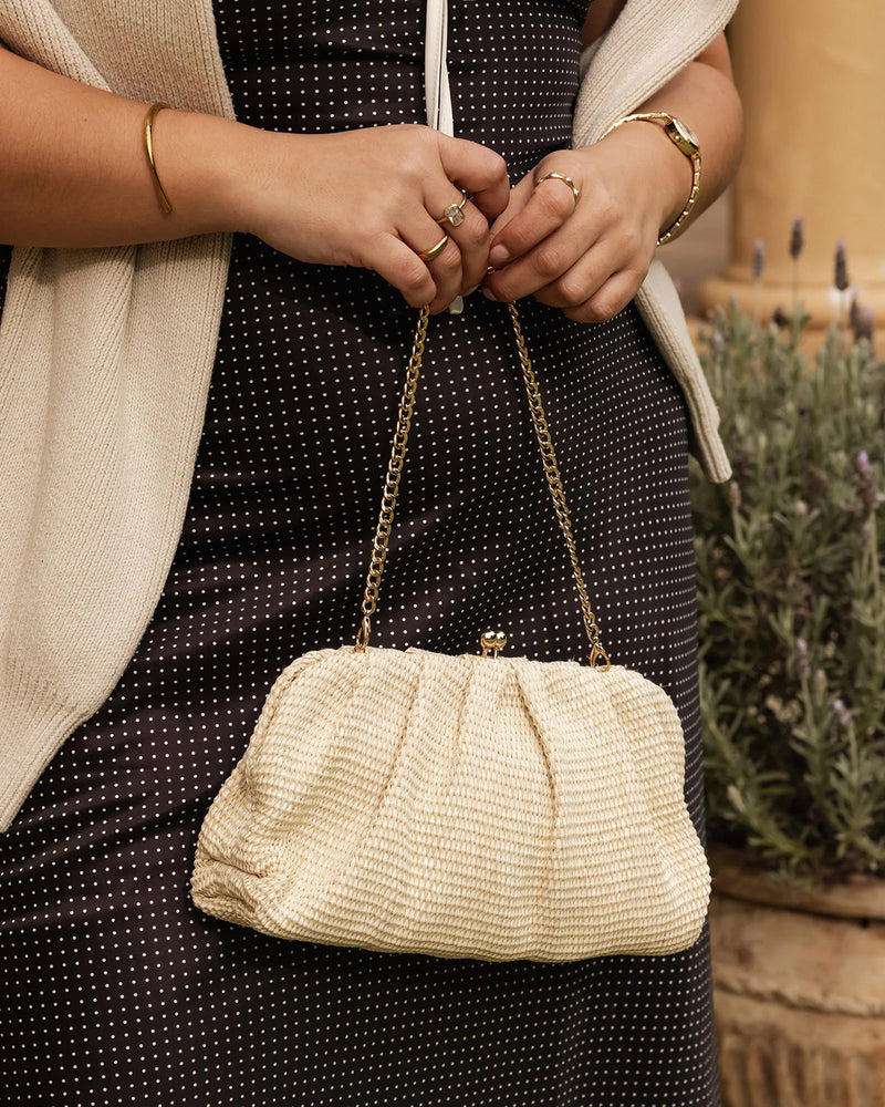 he Goldie Raffia Vanilla Clutch is your statement plus-one for any occasion, designed to elevate your look from daytime celebrations to evening soirées. This evening clutch features a slouchy yet structured silhouette, crafted in a raffia-like texture for a modern take on timeless texture. As a true gold chain clutch, Goldie Raffia Vanilla is finished with both a short and long gold chain strap, giving you the freedom to wear her in hand, over the shoulder, or crossbody. A polished kiss clip closure keeps y