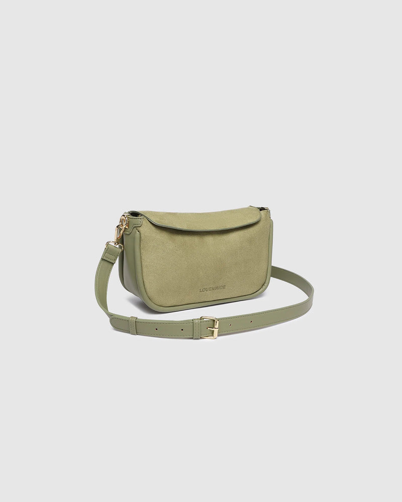 The Louenhide Saylor Sage Green Crossbody Bag brings a bold yet refined edge to your everyday styling. With its soft faux suede finish and sleek baguette-shaped silhouette, this cross body bag with chain detailing blends texture and refinement in all the right ways. Designed to be worn with ease but styled to stand out, the Saylor Sage Green moves effortlessly from day to night, adding impact to your layered winter looks. Wherever the day leads, this chain strap handbag is the finishing touch that completes
