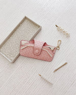 The Louenhide Skittle Sunglass Case is the perfect blend of style and functionality for your everyday eyewear. For ultimate convenience, effortlessly attach to your keys or handbag with the light gold hardware keyring clasp. Without compromising on style, the exterior features a gorgeous vegan leather, while the interior is lined with soft suede material to keep your everyday eyewear protected. Whether it's your favourite sunglasses or your reading glasses, they will stay protected and safe with the secure 