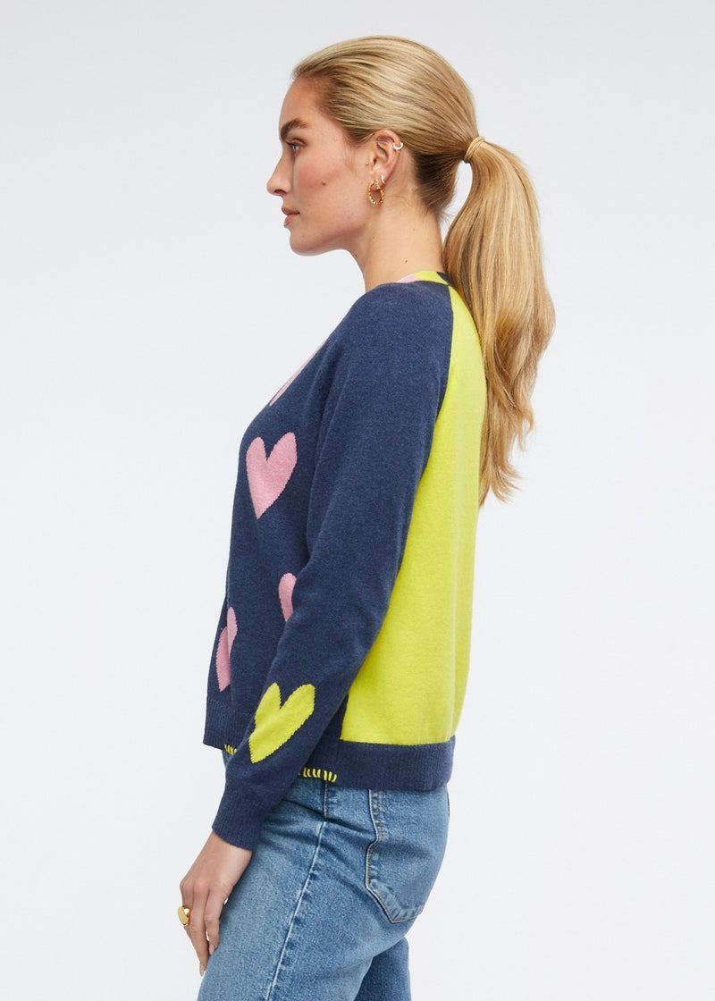 This adorably fun little cardi features pink hearts against a dark denim with a bright yellow back and cuff. Knitted from cotton and cashmere by Zaket & Plover.