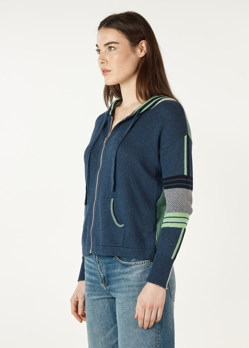  softly knitted hoodie of 5% cashmere and 95% cotton features a zipped front, pockets and feels beautiful to wear. The base colour is navy denim with a grey hood (that is edged with green stripes), Green and grey stripes and checks are features on the arms and also the back.