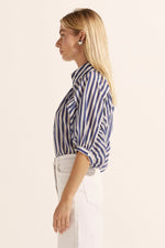 A high neck stand and a row of covered buttons leads into a gathered bodice and sleeve. These gathers create a distinctively feminine aesthetic. Scalloped lace trim injects a romantic notion to this modern and confident piece. Crafted in a light-weight ramie the Adage teams delightfully with denim or with a tailored pant.&nbsp;