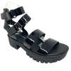 A gladiator inspired sandal in black patent has a chunky black sole, soft footbed and is fastened at the ankle with velcroe and two silver rings. Made by Django & Juliette.