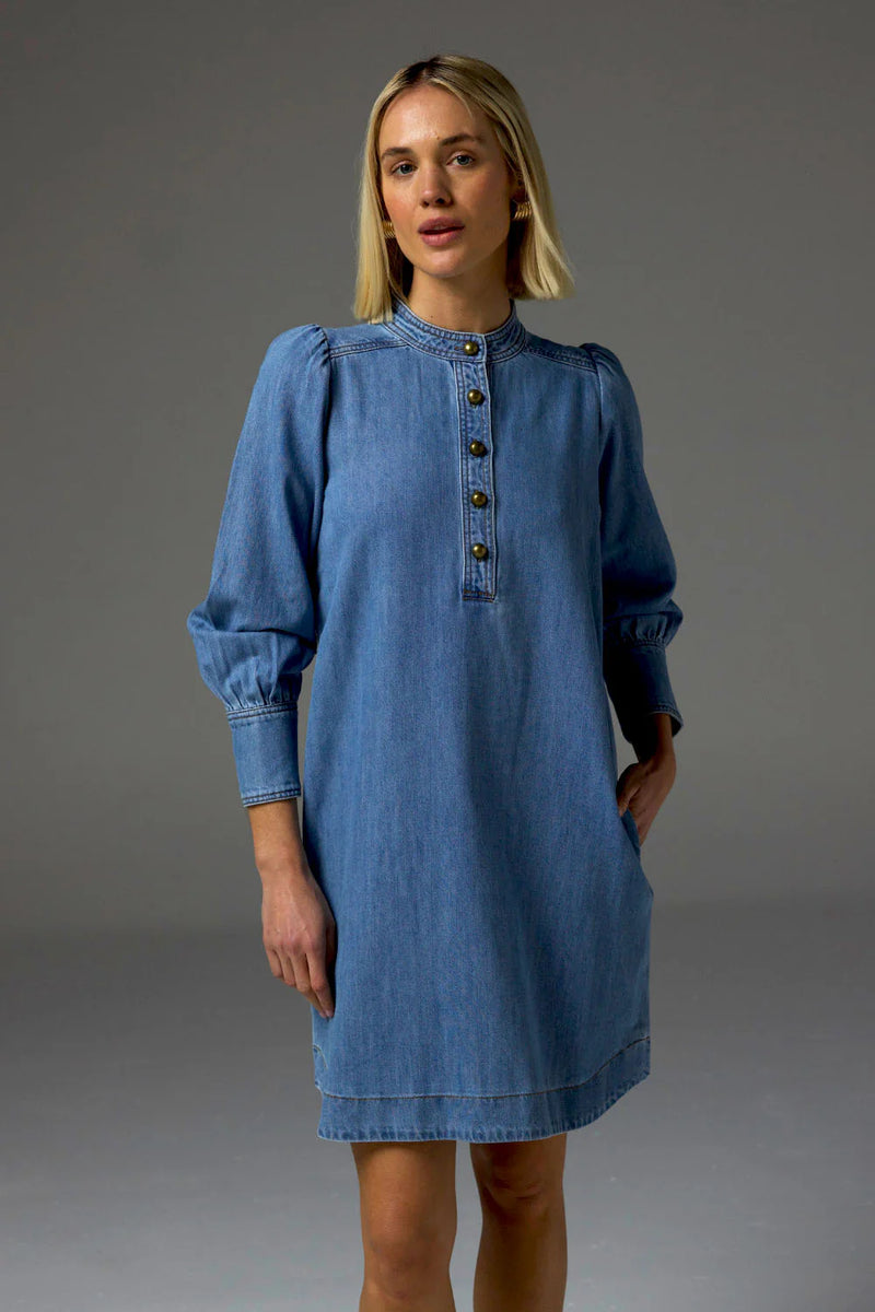 The Elocution dress is inspired by vintage denim styles, featuring a scooped hemline and refined domed brass buttons, make it a standout denim piece.&nbsp;

Style with a sling back flat or boot for a timeless, fall-friendly ensemble.