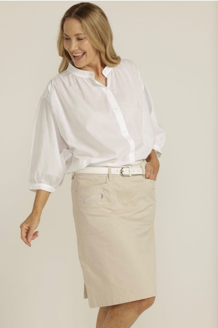 This handy knee length skirt in a beige fabric consisting of 97% cotton and 3% spandex has a button at the waist, a fly, back and front pockets and a zip at each front pocket. It has belt tabs and also features a double kick pleat at the back.