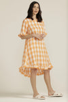 This 100% linen apricot gingham dress is light and cool for our summer months. It has a round neck, a yoke from which a flared bottom falls, buttons at the back and a swooped hemline. The short sleeve and the hemline are finished with a 6cm ruffle. And there are also pockets!