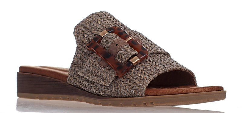 Made from manmade materials this low wedged slide has a comfortably padded footbed, flexible sole and a wide band of raffia across the foot finished with a large tortoise buckle.