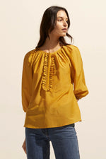 Soft gathering off the neckline creates a curved and feminine aesthetic in this piece. Neat ruffles frame the ¾ placket providing poise and polish.    Colour: Ochre