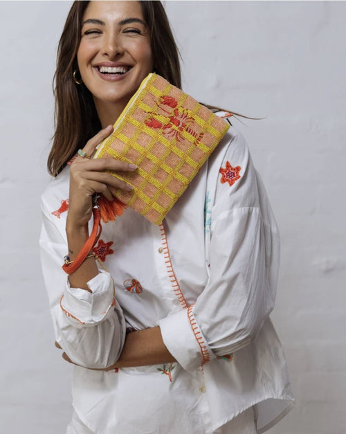 This fun little beaded clutch features an orange embroidered lobster with a background of peach and orange check. The back of the bag is orange canvas. The zipper has two pompom's dangling from it. There is also a wrist strap for convenience. It measures 19cmx17cm.