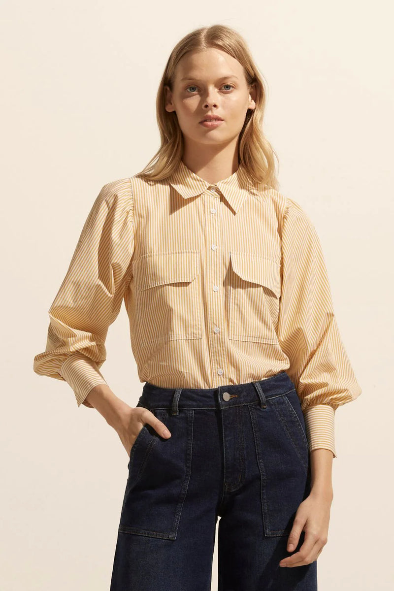 The Underpin is a feminine and spirited take on the classic button-through shirt, a gathered shoulder and cuff create a blouson sleeve that provides a flourish and contrast to the traditional shirting elements.    Colour: Ochre Stripe