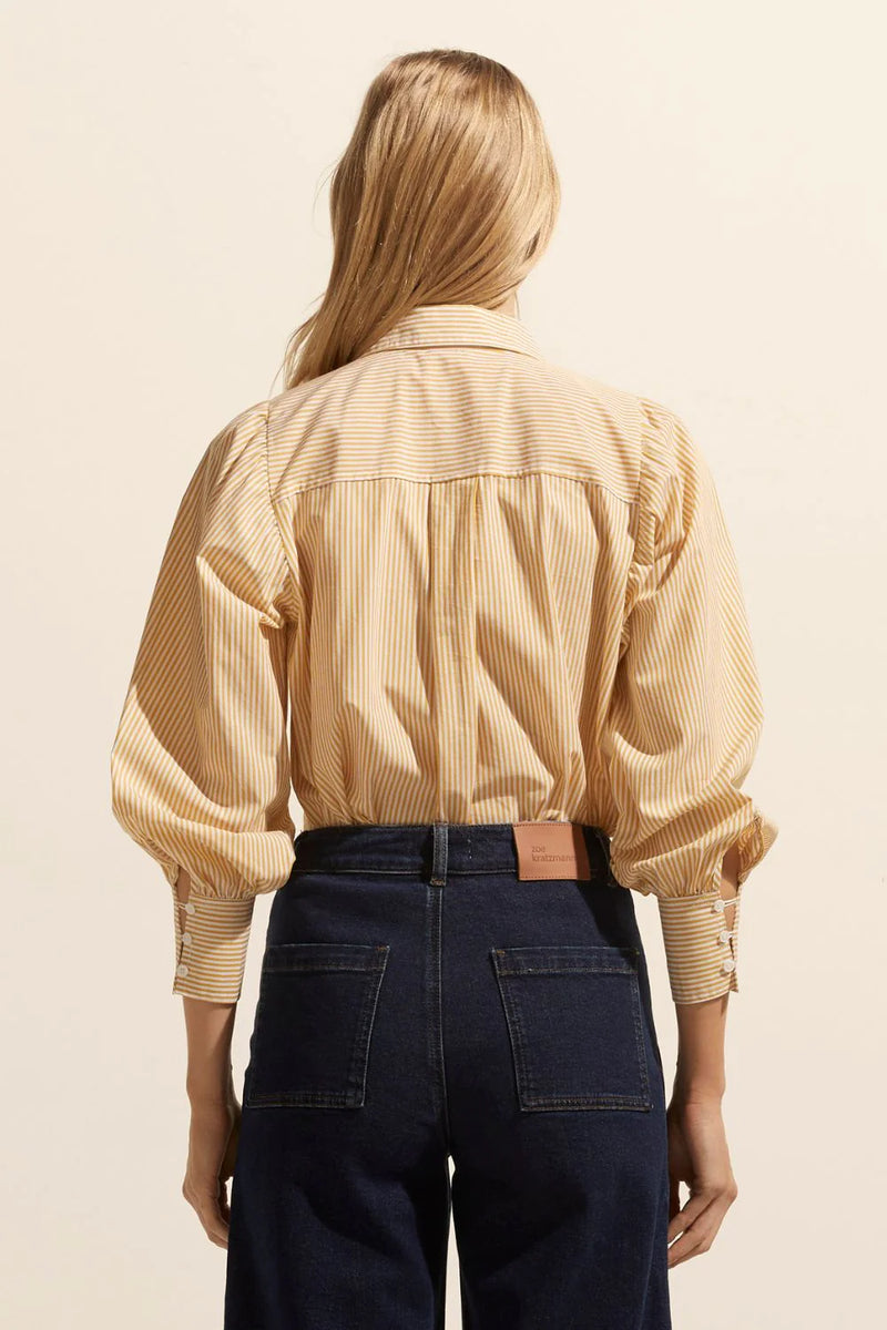 The Underpin is a feminine and spirited take on the classic button-through shirt, a gathered shoulder and cuff create a blouson sleeve that provides a flourish and contrast to the traditional shirting elements.    Colour: Ochre Stripe