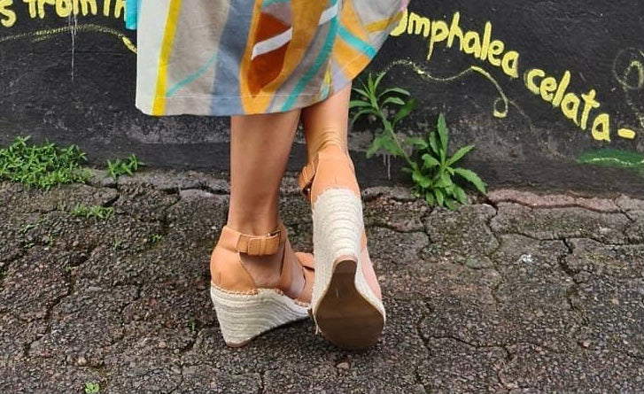 Espadrille wedges with tan strapping around toes and ankle. Buckle around ankle and knotted leather across toes.