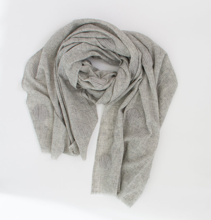 This elegant light weight scarf is made of 50% wool, 30% nylon and 20% cotton. It is a mono tone with the interest being a large dot of wool stitched at intervals. Colour is grey.