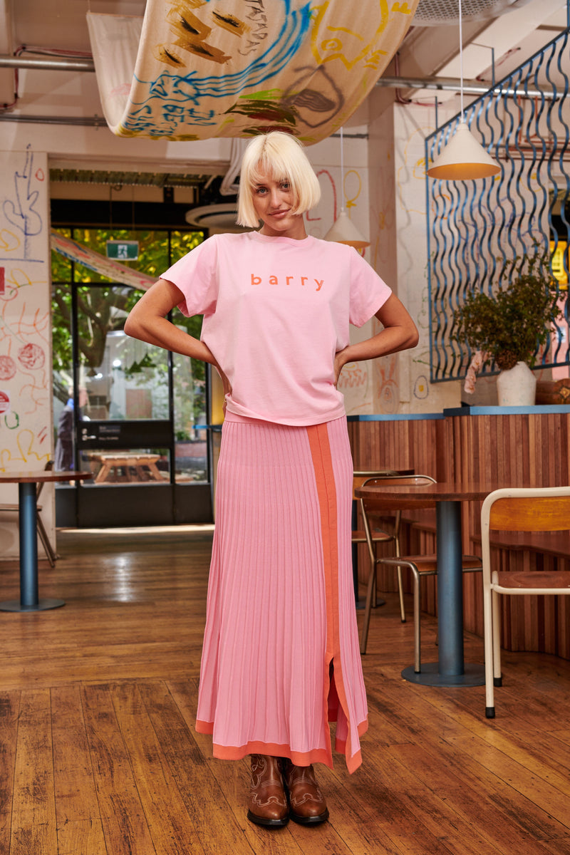 The Barry Made Davy Skirt is knitted for a light springy handle with tactile ribs that create the effect of rippling pleats for beautiful movement and volume. It's a versatile skirt, in vibrant pink with tangerine orange trims around the hem for all lovers of colour! Detailed with a small split at the front and a comfortable elastic waistband.  Composition: Viscose/Nylon