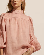The Pace top is a culmination of elevated feminine style and simplicity. Cut in a luxurious ramie, the fabric evokes a romantic and artisanal air. Ladder lace trim and covered buttons add to its allure. A high neckline and lantern sleeve provide drama in this stunning piece. The Pace is a head turning addition to autumn dressing and is sure to impress whatever the occasion.   