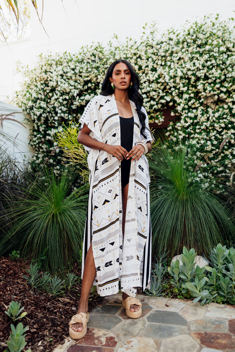Made by Possi in soft 100% viscose this glamorous long kimono is the perfect holiday piece. Wear over swimmers or dress up for lunch or a casual dinner. The tribal print with splashes or gold and silver has a waist tie of black and white stripe.  Available in long or short length.  Sizes  -  S/M  L/XL